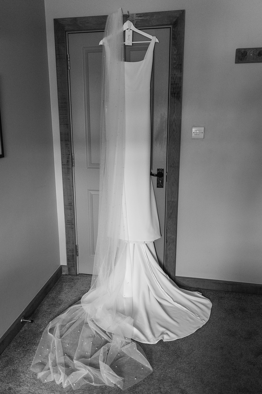 Bride's dress hanging up at a Bury Manor Barn Wedding in Sussex. Photographer OliveJoy Photography.