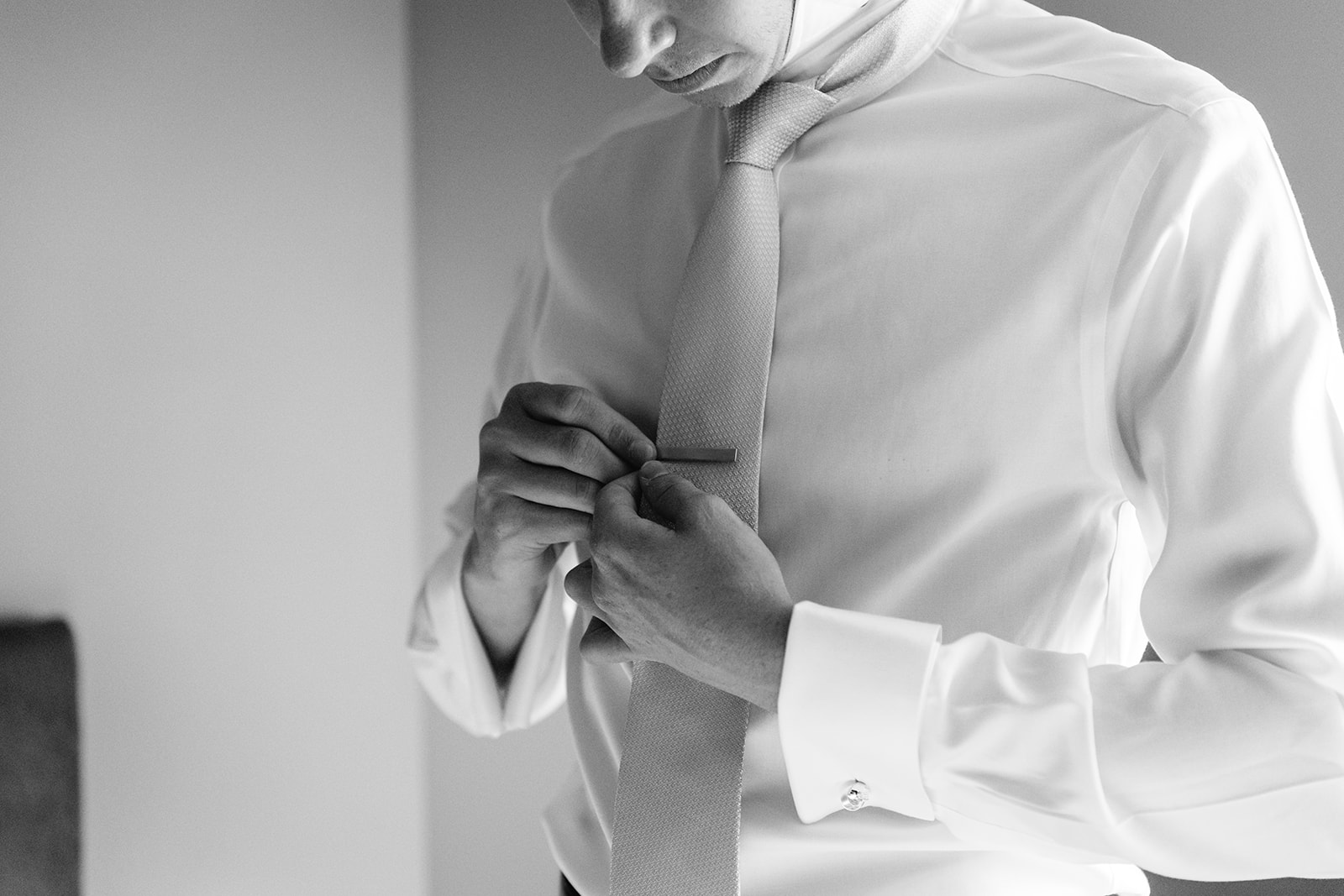 Groom buttoning shirt at a Bury Manor Barn Wedding in Sussex. Photographer OliveJoy Photography.
