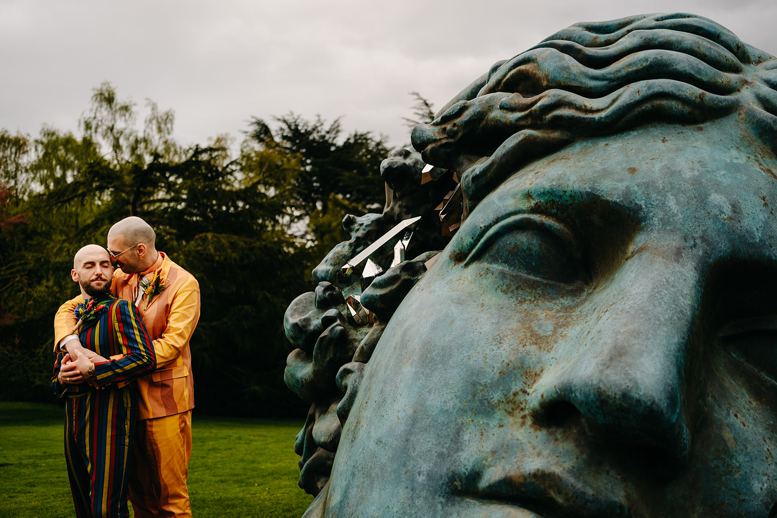 Gay couple embrace next to sculpture at Yorkshire Wedding Venue