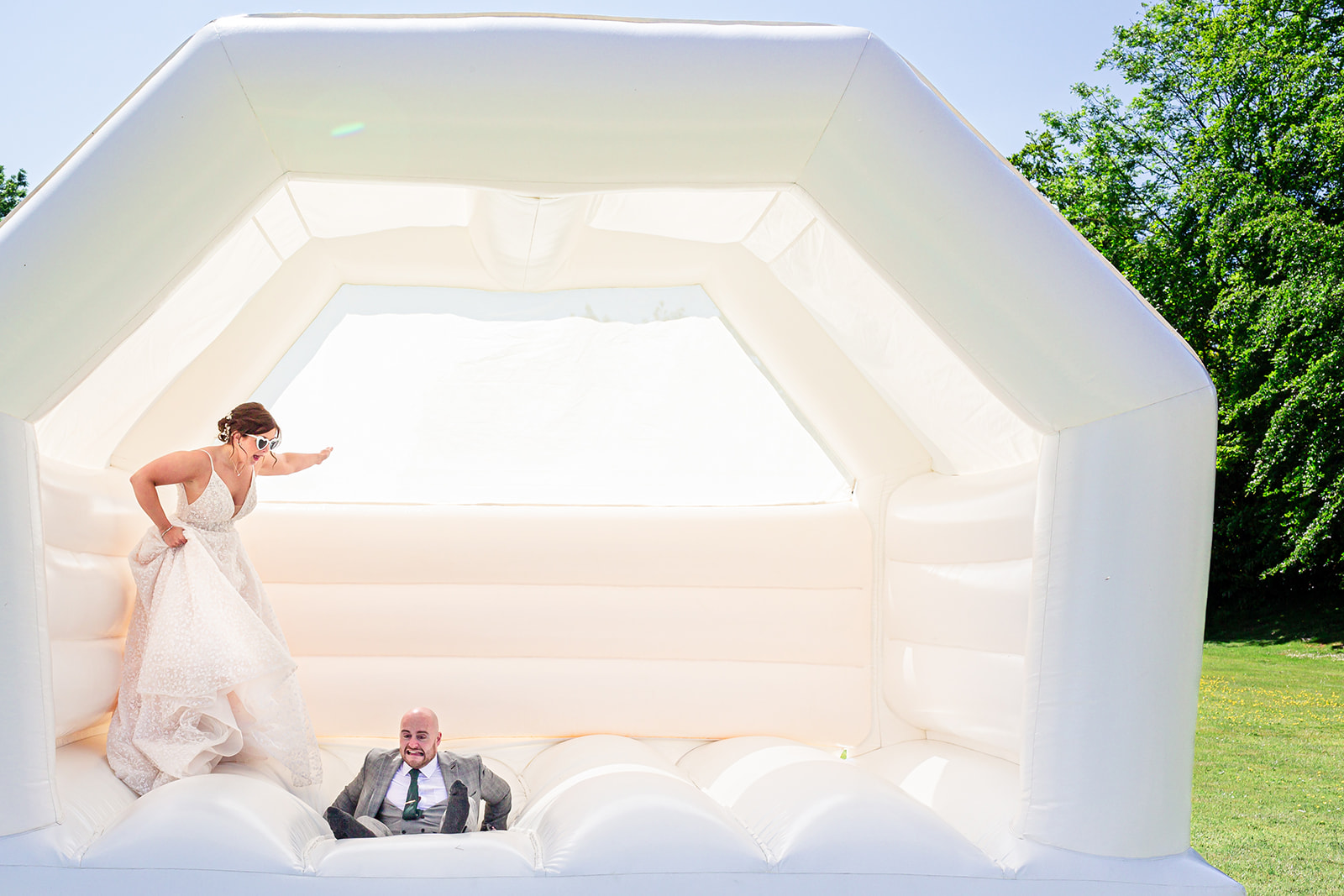 Newly married couple enjoy some fun time on the bouncy castle in the Brendenbury Court Barns gardens