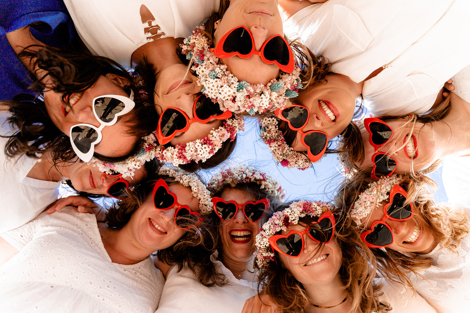 Accessoires de séance photo EVJF : lunettes de soleil assorties portées par un groupe d'amies sur la plage.