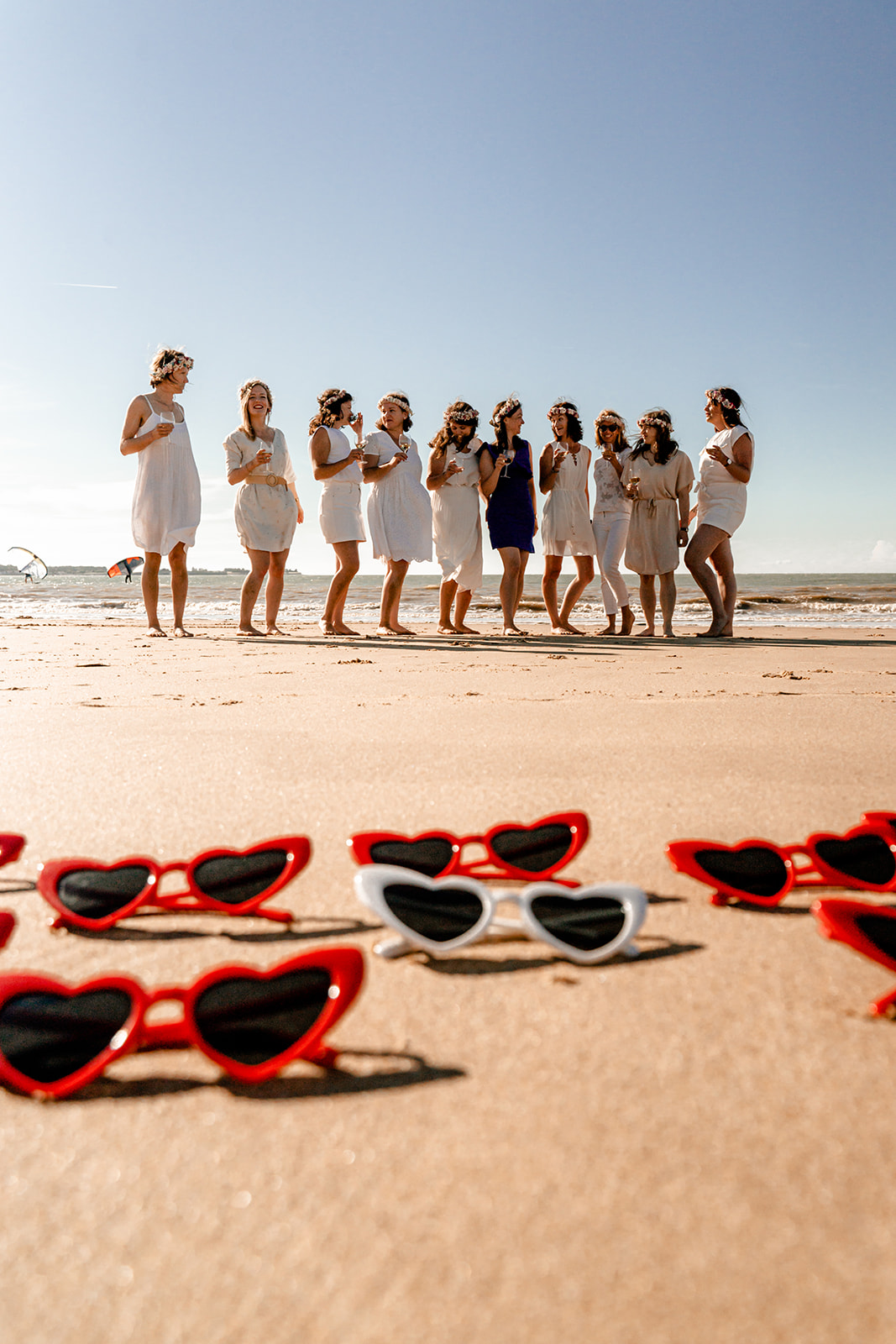 Accessoires de séance photo EVJF : lunettes de soleil assorties portées par un groupe d'amies sur la plage.