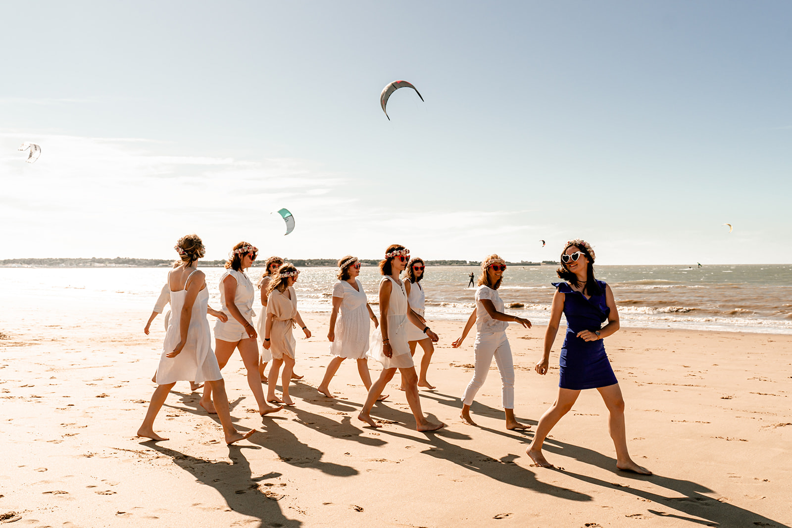 Groupe de jeunes femmes en robes d'été blanches riant ensemble sur une plage de l'Île de Ré.