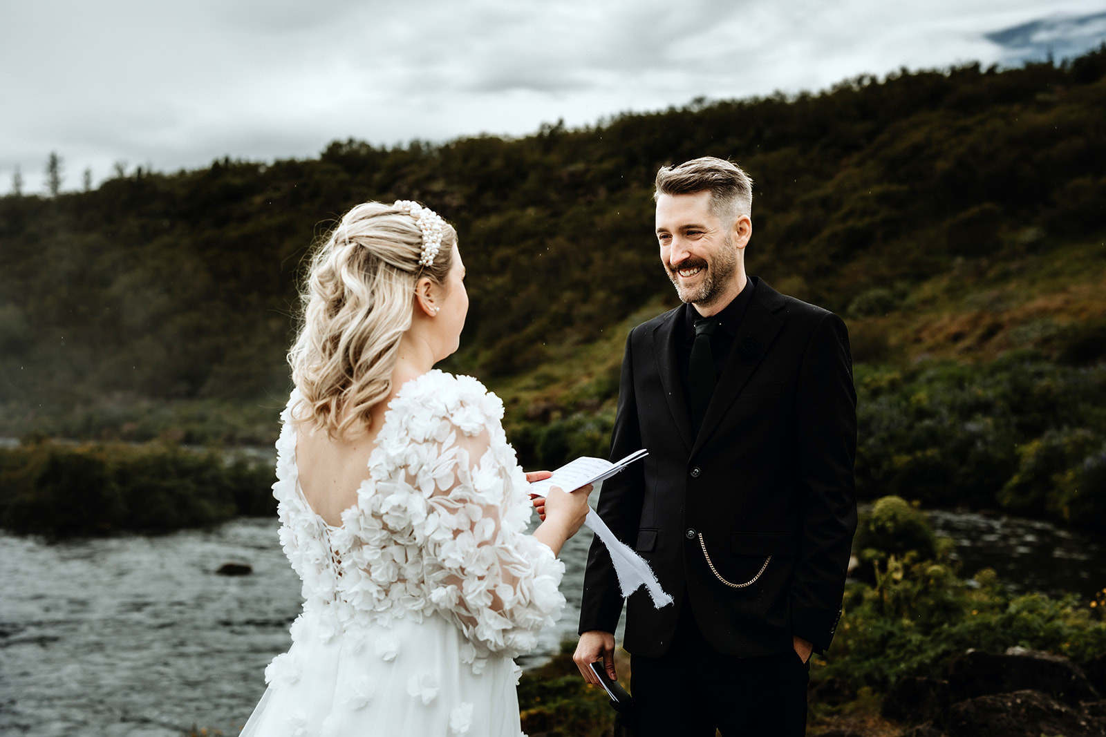 Waterfall ceremony in Iceland. Bride and groom are standing in front of a waterfall and exchanging their vows.