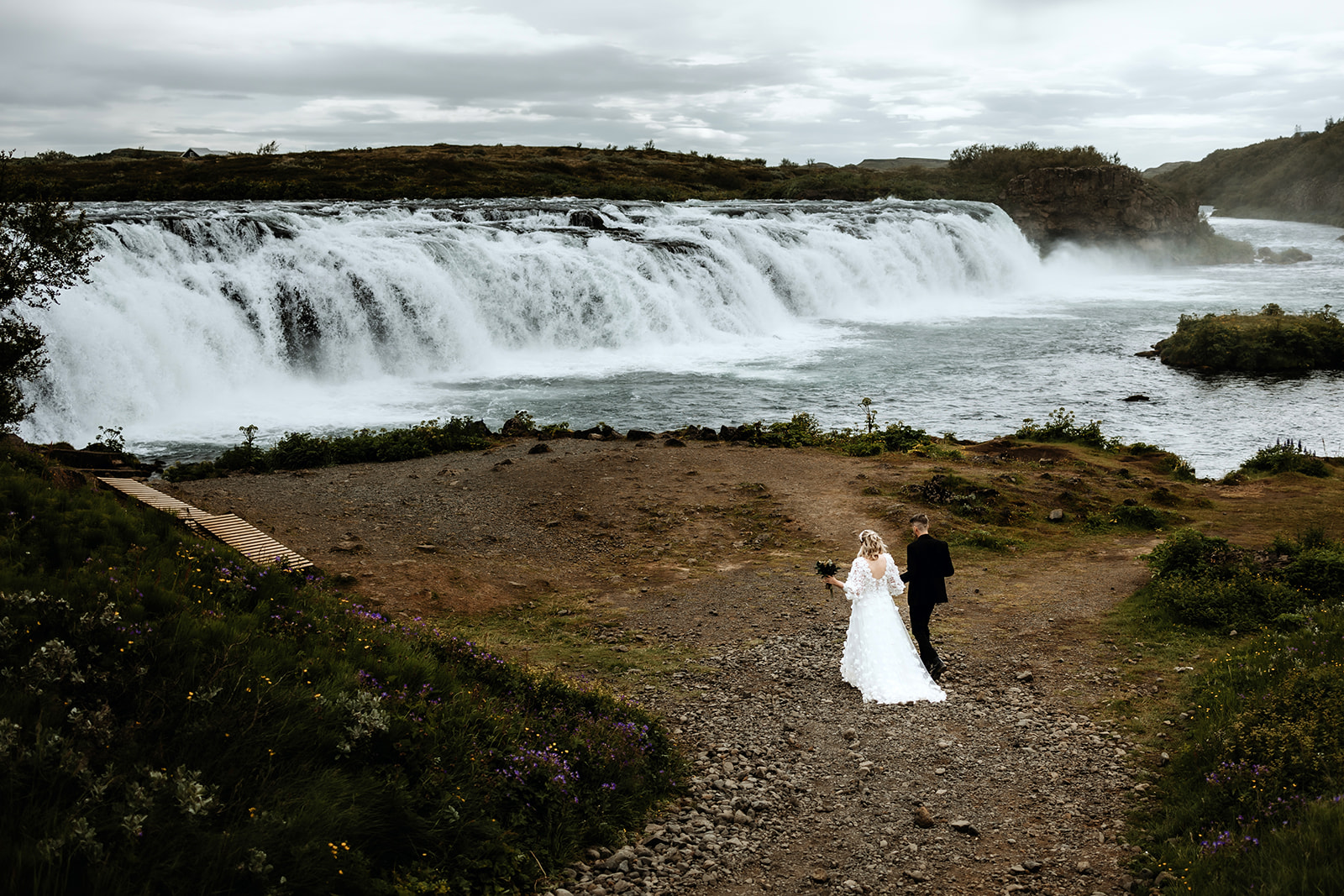 Bride and groom are walking to the waterfall where they are exchanging their wedding vows.
