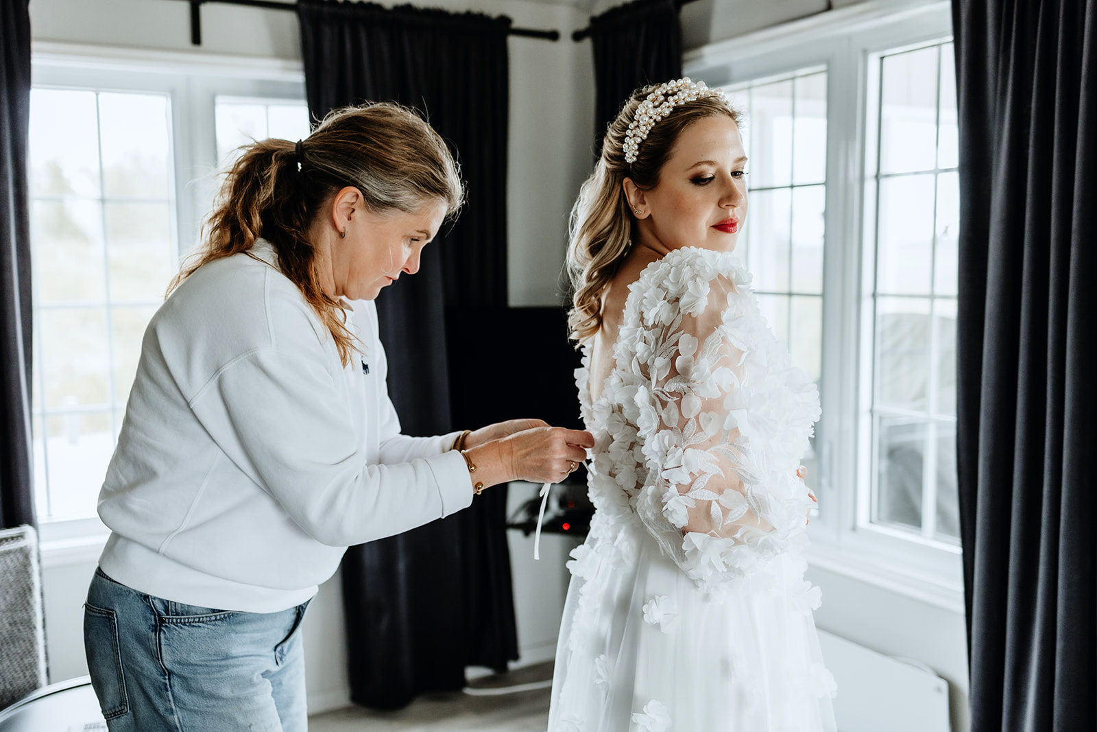 Bride is getting ready and putting her wedding dress on with the help of her makeup artist in Iceland.