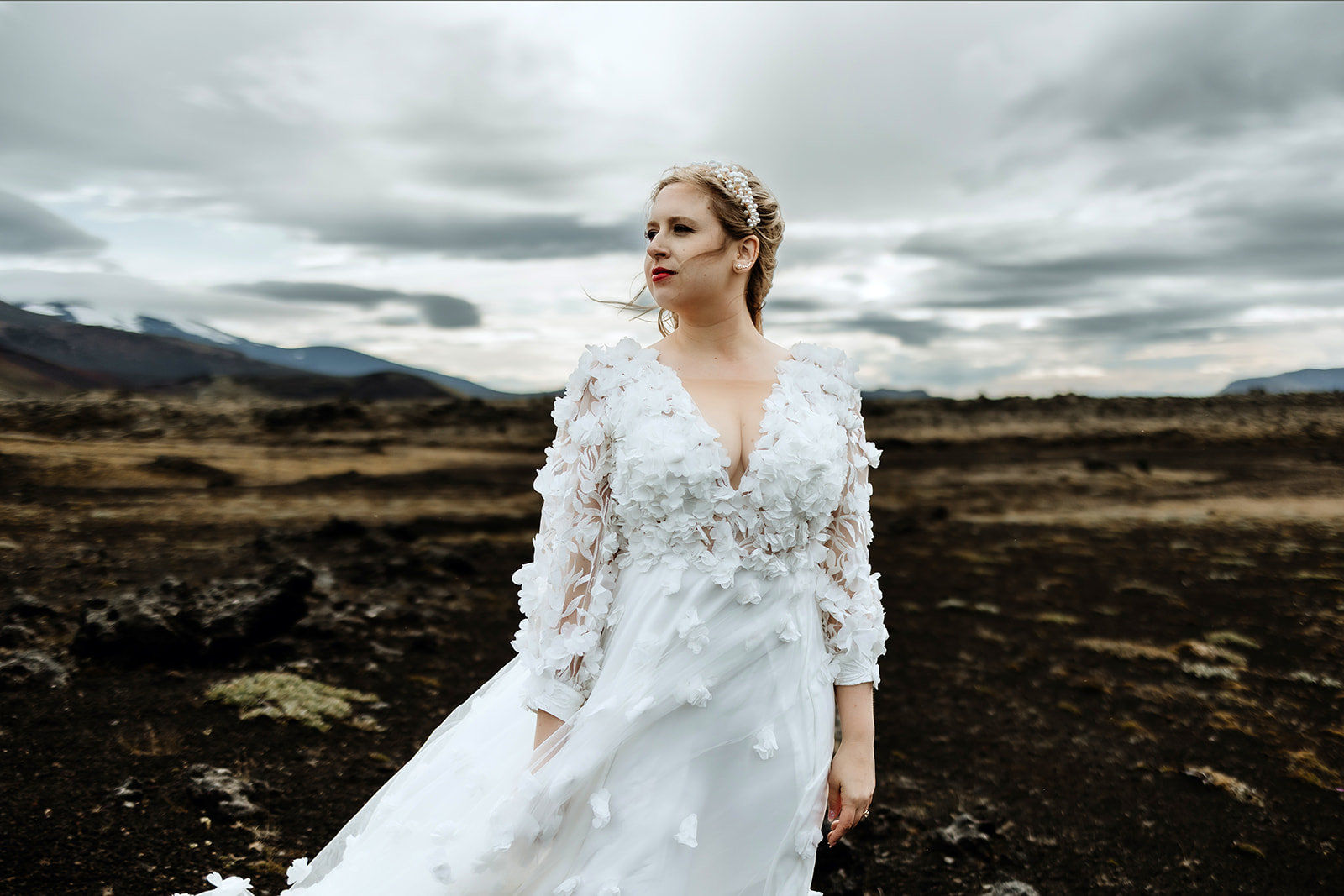 Brideis standing in the moody landscape of the Icelandic Highlands with dramatic sky.