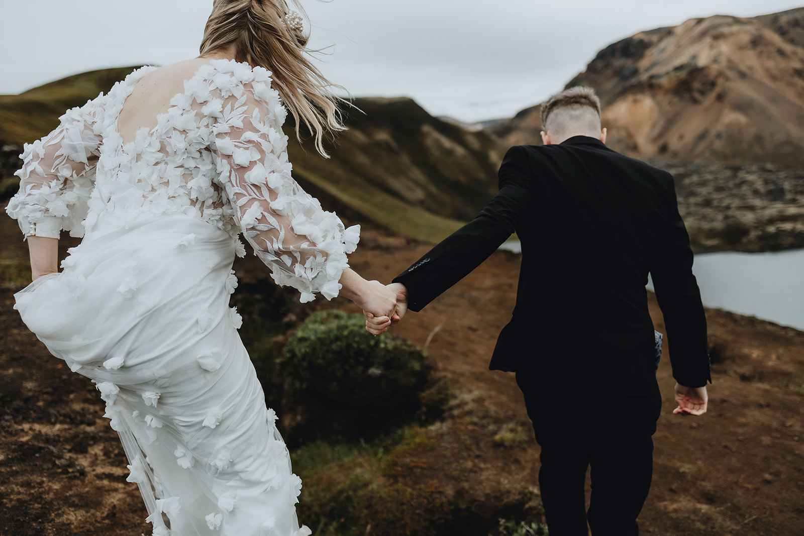 Bride and groom are climbing on a hill in the dramatic highlands of Iceland