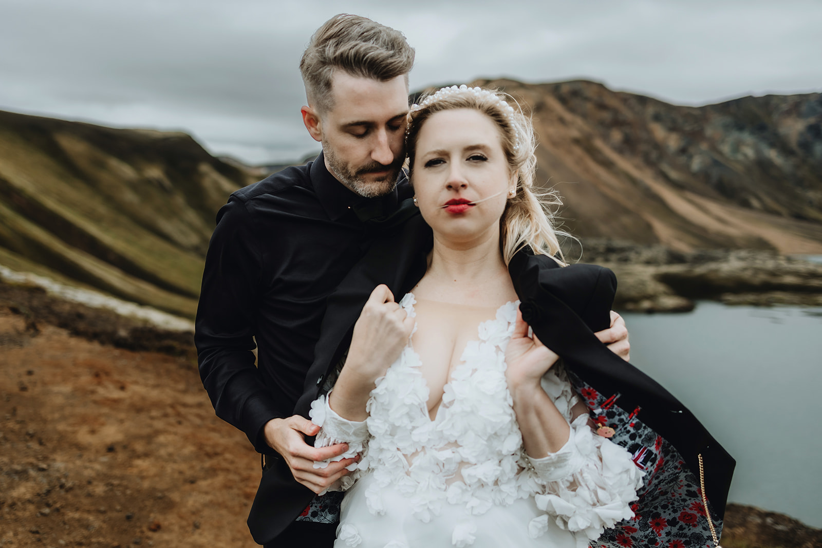 Groom is covering his wife with his wedding jacket from the cold weather in Iceland