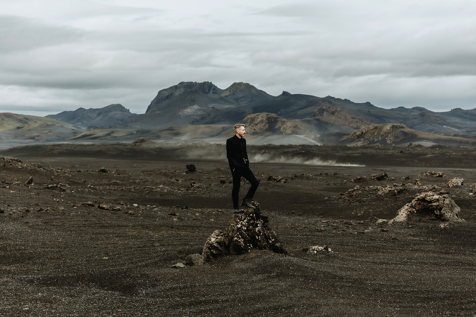 Groom is standing in the moody landscape of the Icelandic Highlands with dramatic sky.