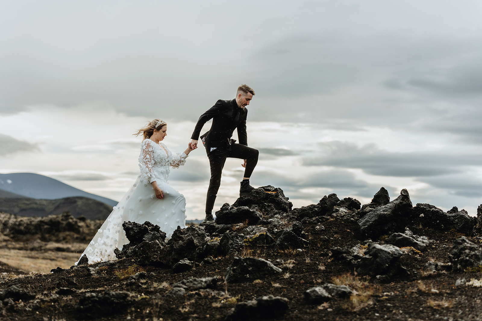 Bride and groom are climbing on a hill in the dramatic highlands of Iceland