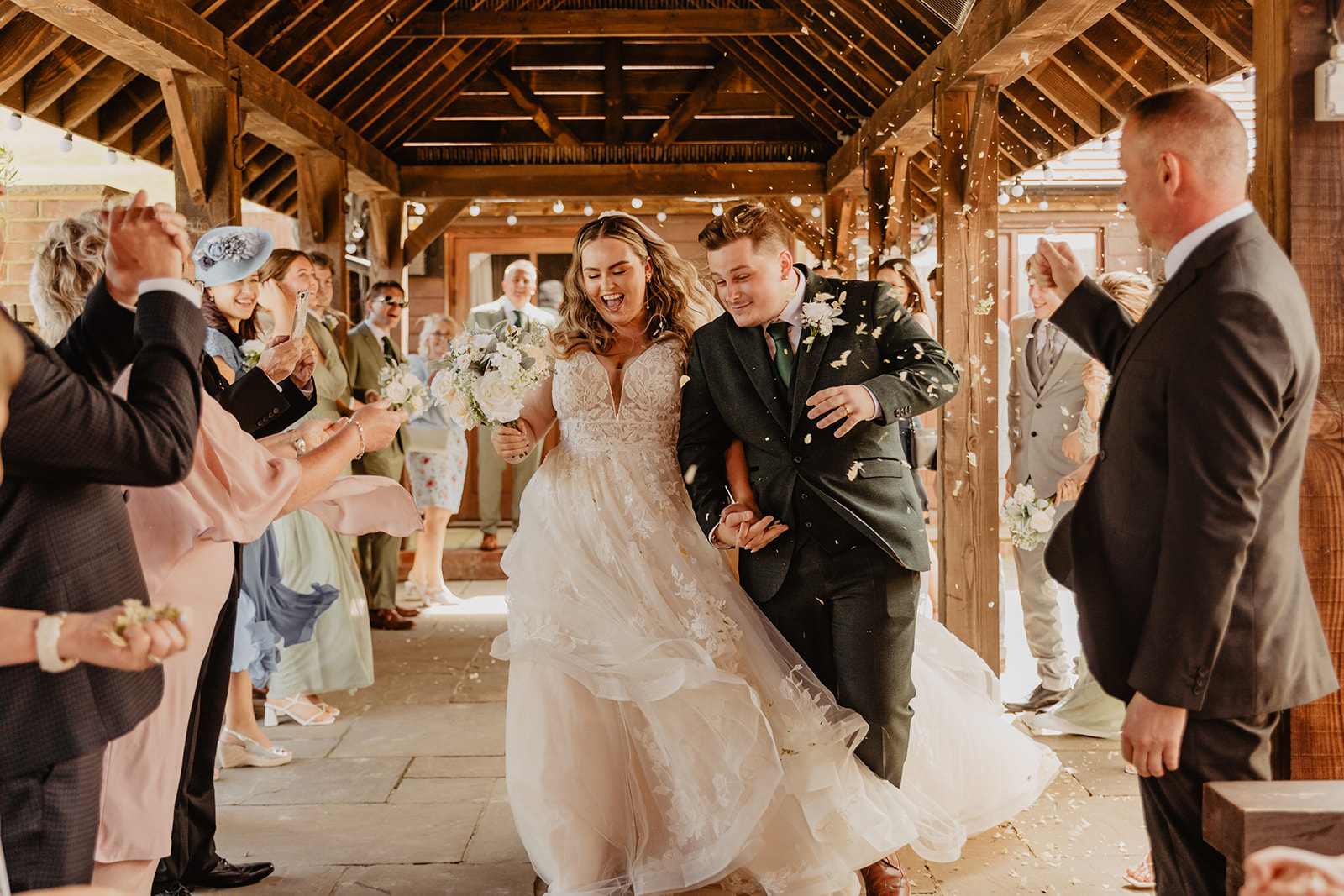 Bride and groom with confetti at a Long Furlong Barn Wedding in Worthing, Sussex. By Olive Joy Photography.