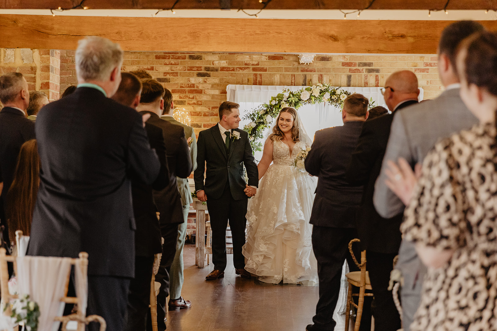 Bride and groom walk down the aisle at a Long Furlong Barn Wedding in Worthing, Sussex. By Olive Joy Photography.