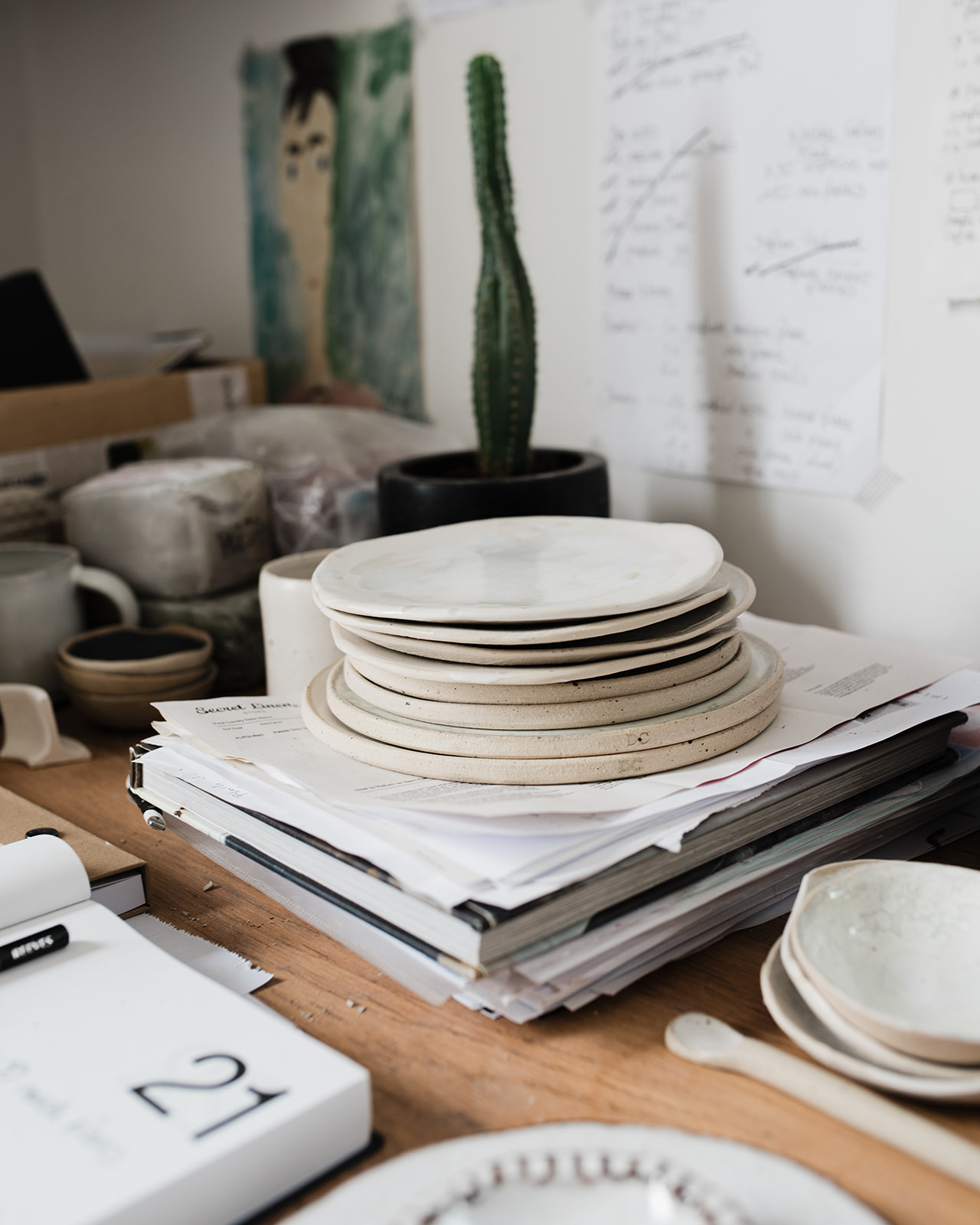 A stack of white handmade ceramic plates in a potter's studio in Essex.