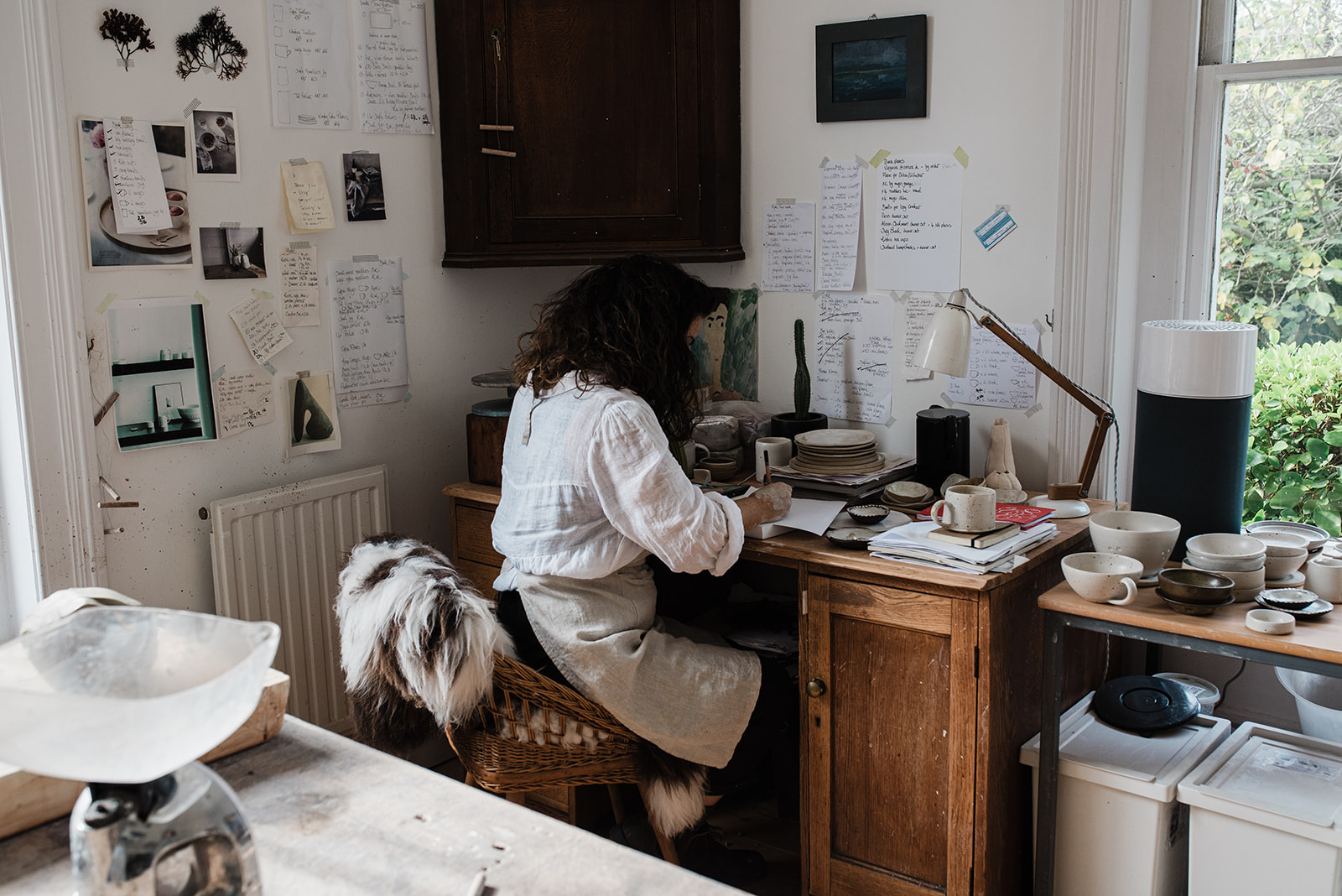 female potter writing at her desk in a light filled studio in Essex.