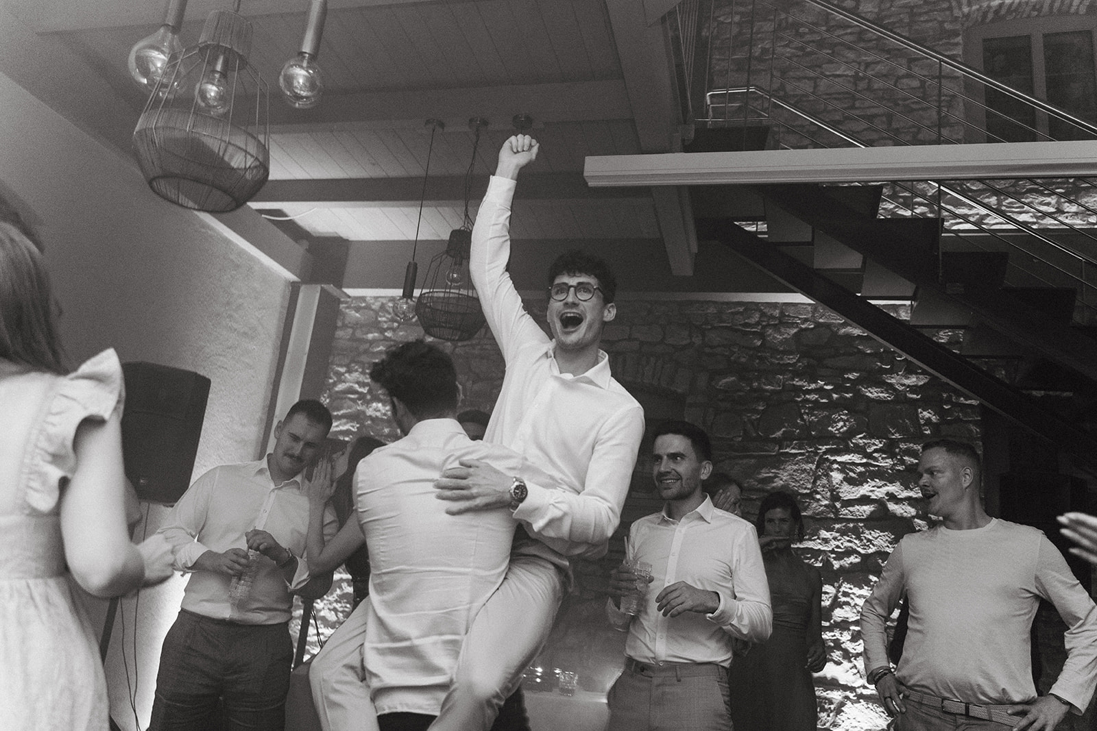 Bräutigam wird von Gast in die Luft gehoben und jubelt dabei mit Faust in die Luft auf der Tanzfläche des Hotel Freihof