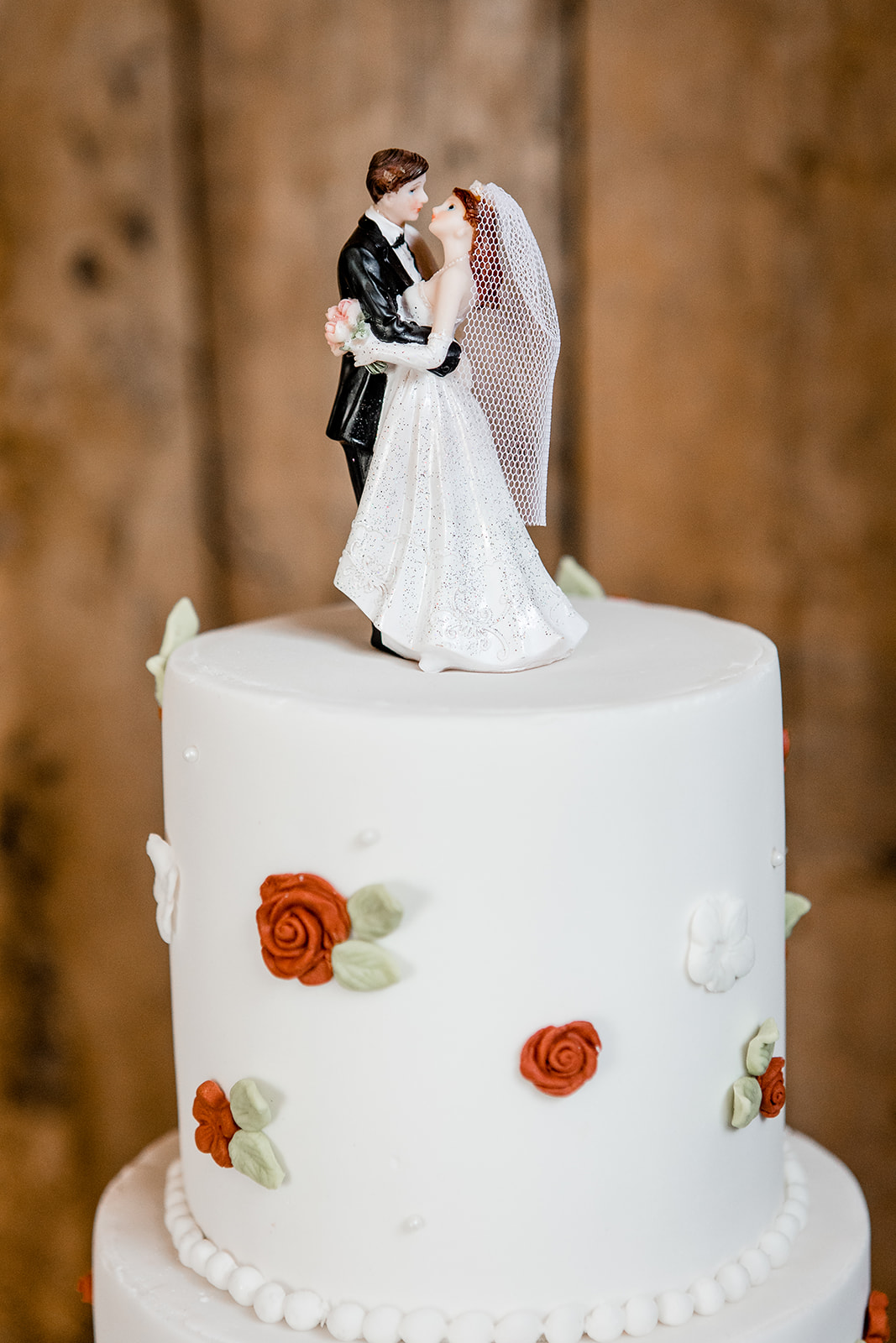 classic cake topper on an iced cake with red roses