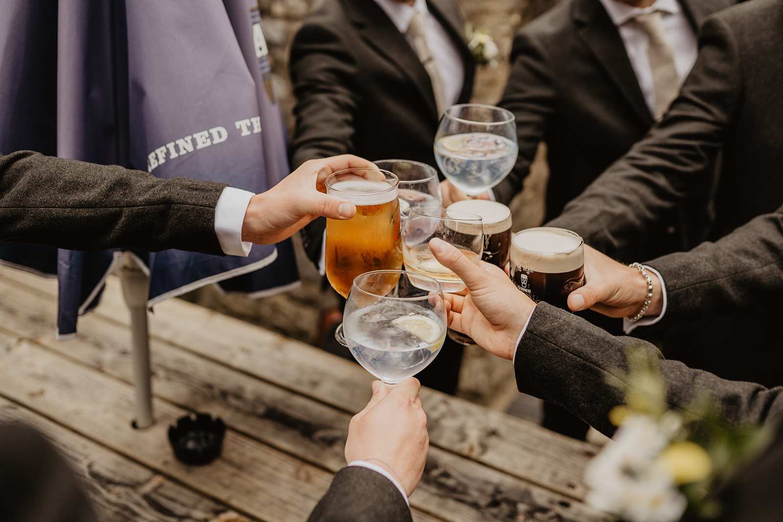 A groom and his groomsman share a drink at a Great Tythe Barn Wedding, Cotswolds. By Olive Joy Photography.