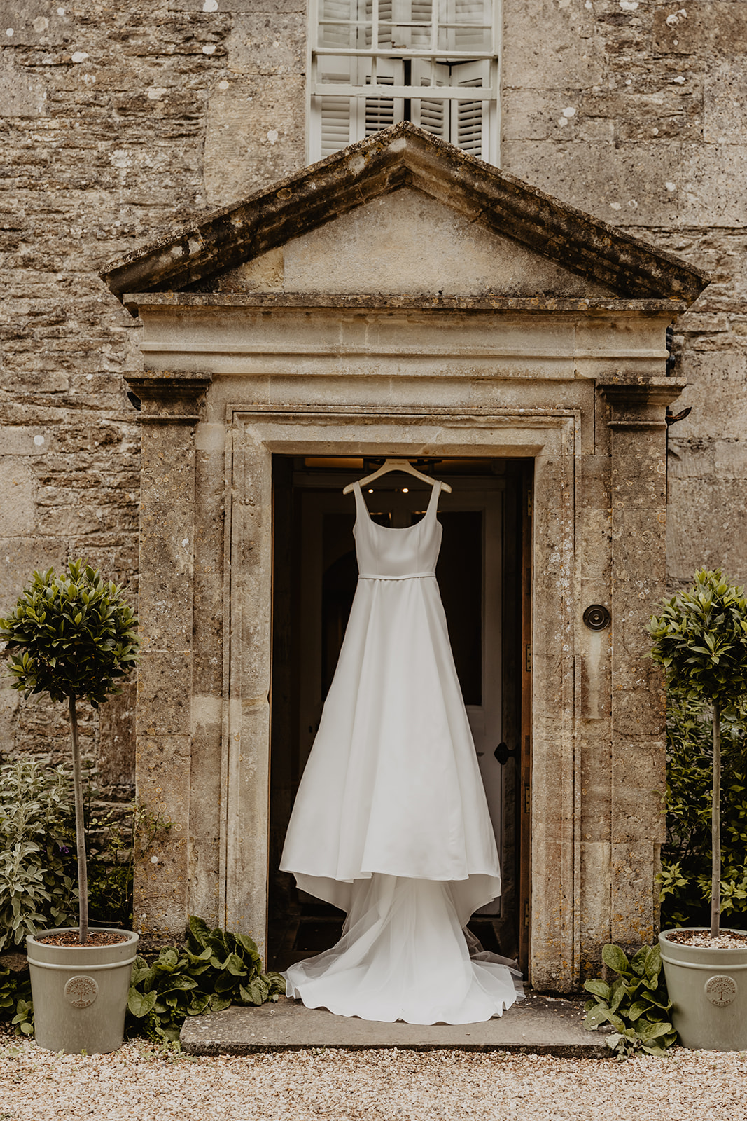 Wedding dress hanging at a Great Tythe Barn Wedding, Cotswolds. By Olive Joy Photography.