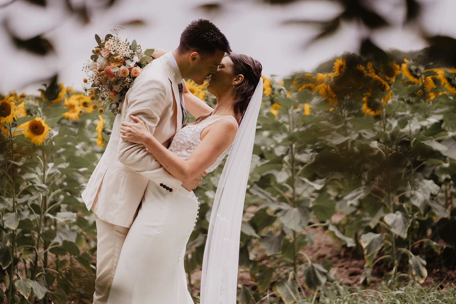 A couple who got married in Charente, France hugging in front of a sunflowers field during their couple session
