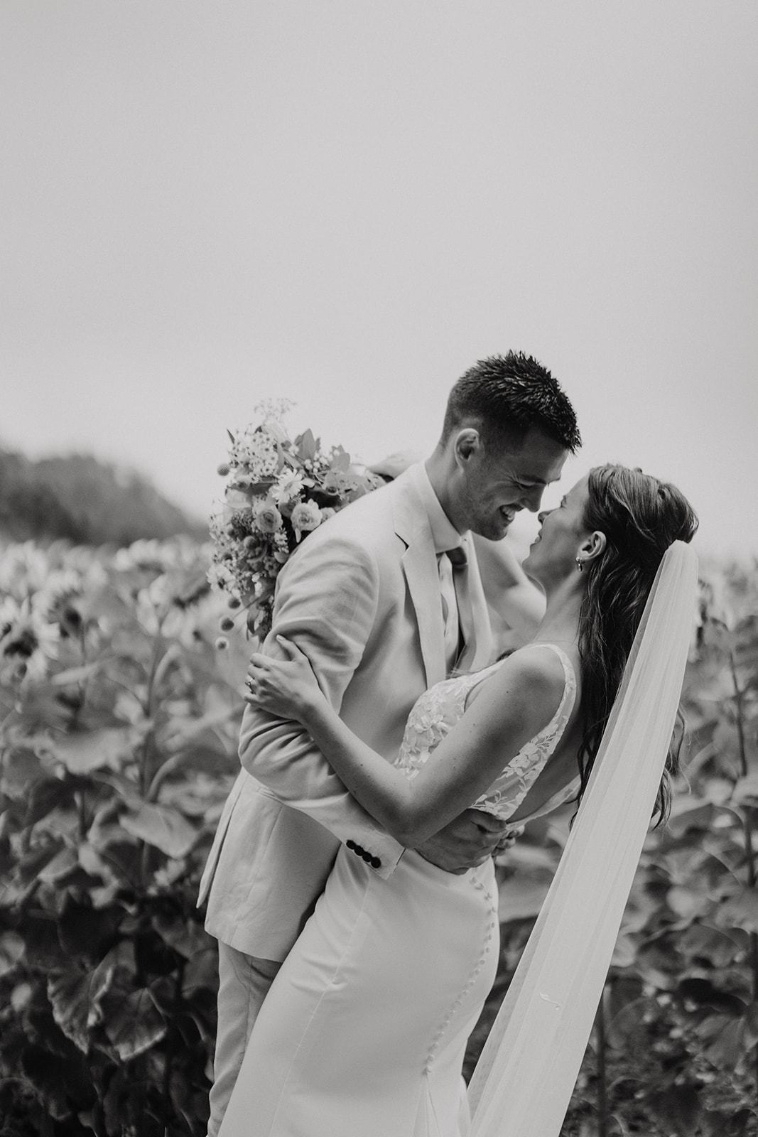 A couple who got married in Charente, France hugging in front of a sunflowers field during their couple session