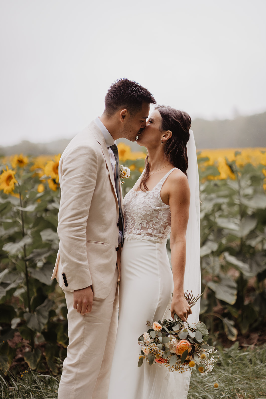 A couple who got married in Charente, France kissing in front of a sunflowers field during their couple session