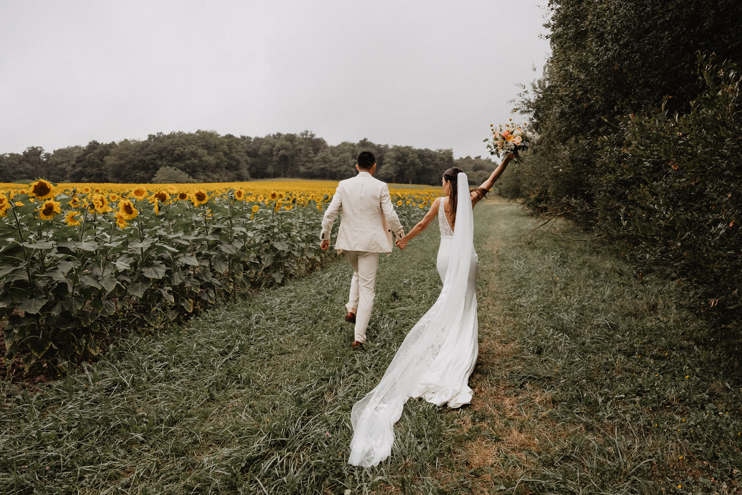A couple who got married in Charente, France running in a sunflowers field during their couple session