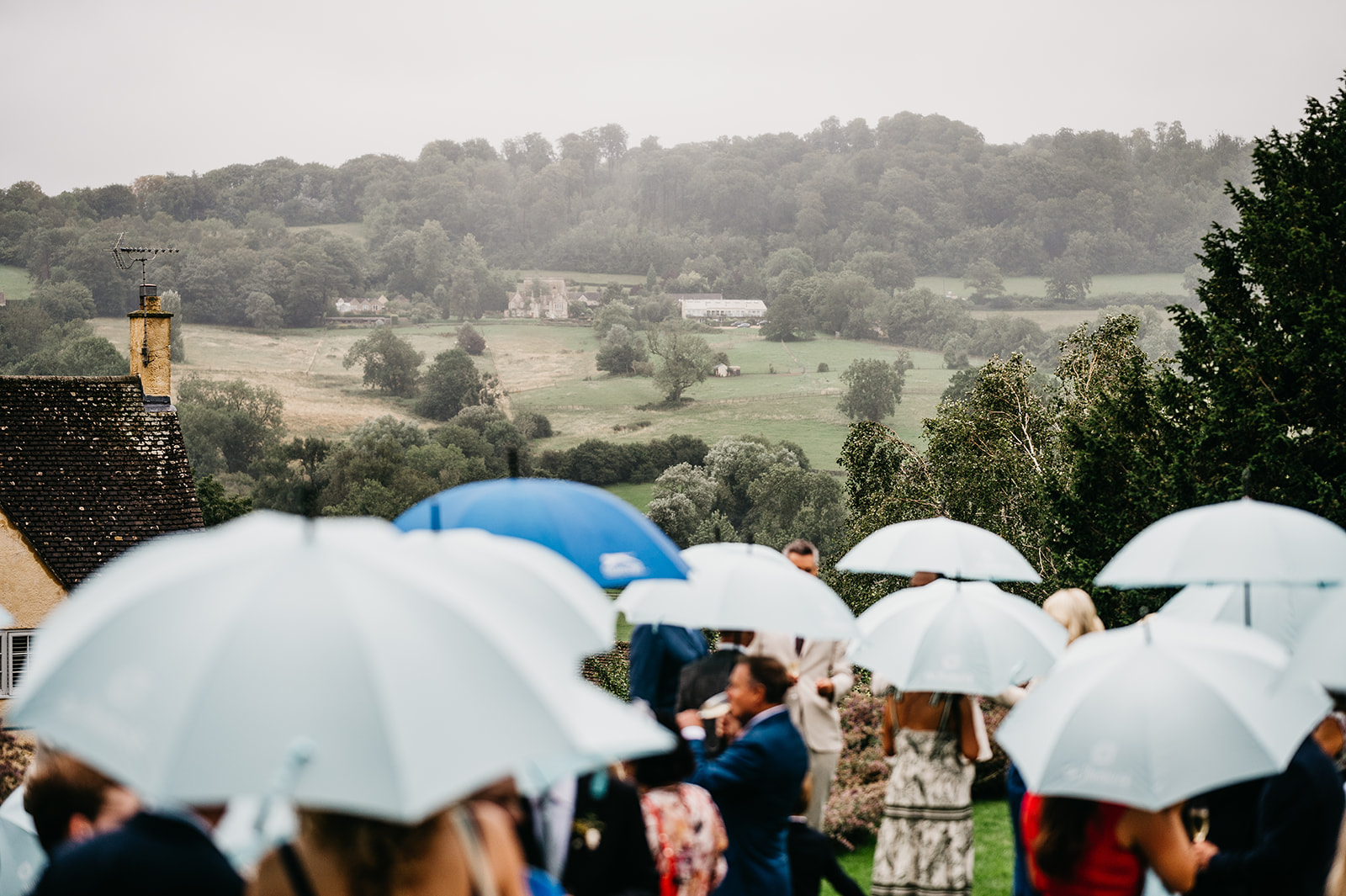 Cotswolds wedding guests with umbrellas