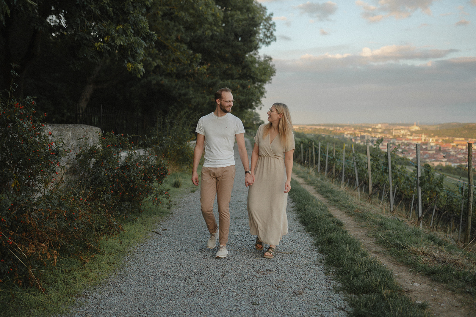 Paar läuft Hand in hand durch die Weinberge und genießt den Sonneuntergang