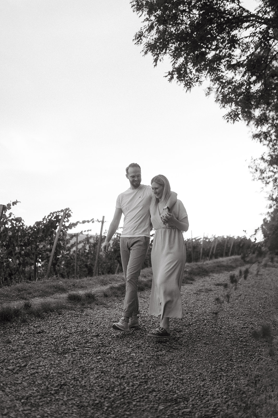 Paar läuft Hand in hand durch die Weinberge und genießt den Sonneuntergang