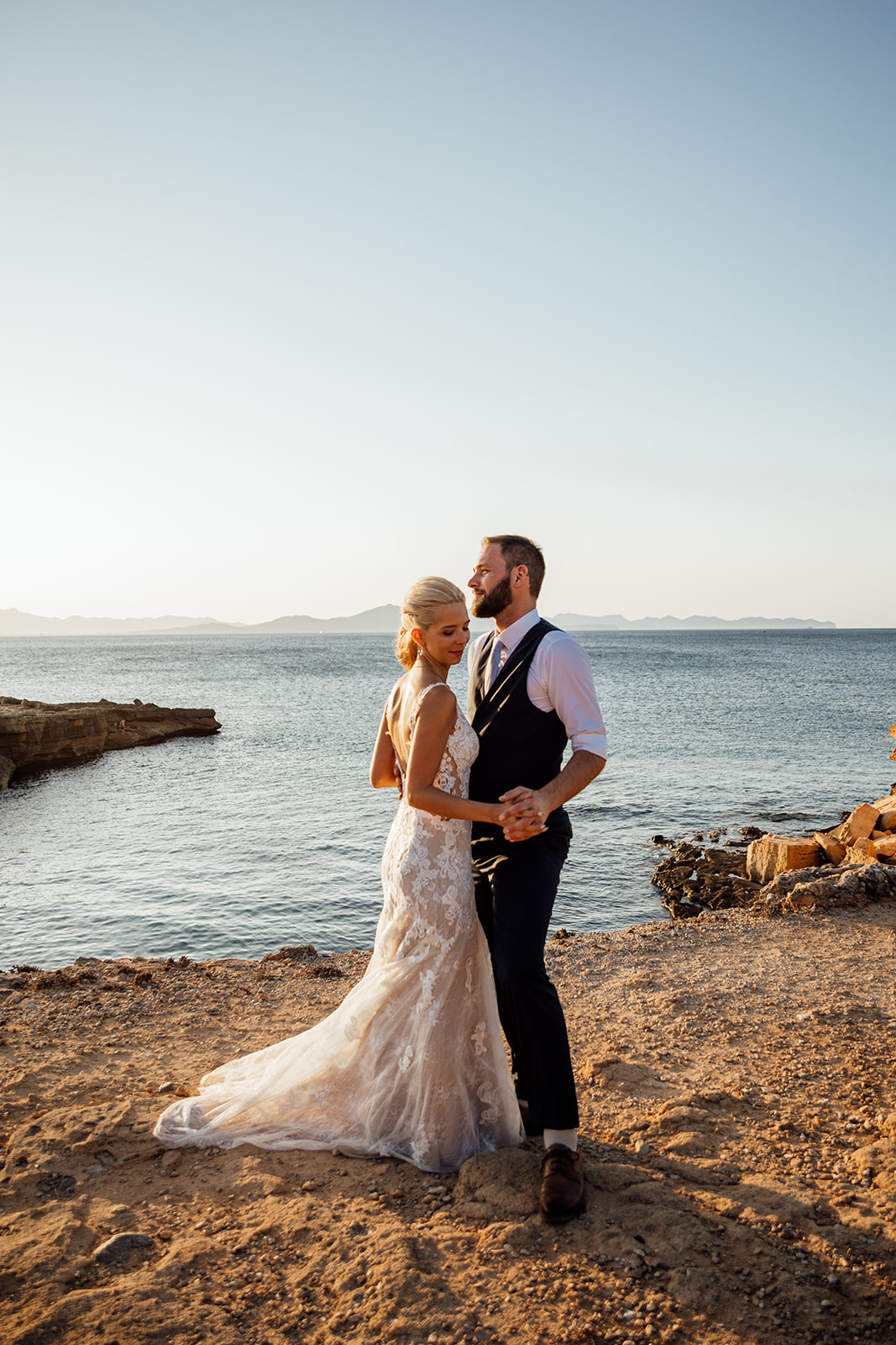 After Wedding Shooting Mallorca - Paar steht am Meer - Sonne im Hintergrund 