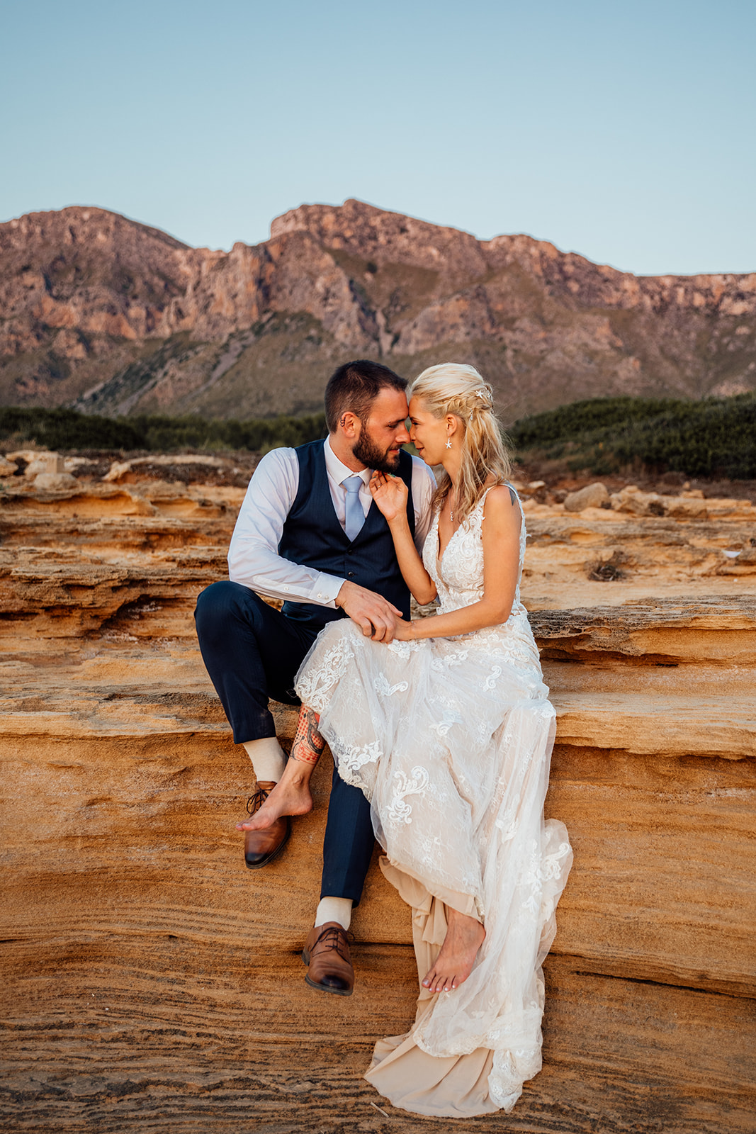 After Wedding Shooting Mallorca - Paar sitzt an Klippen, die orange leuchten 
