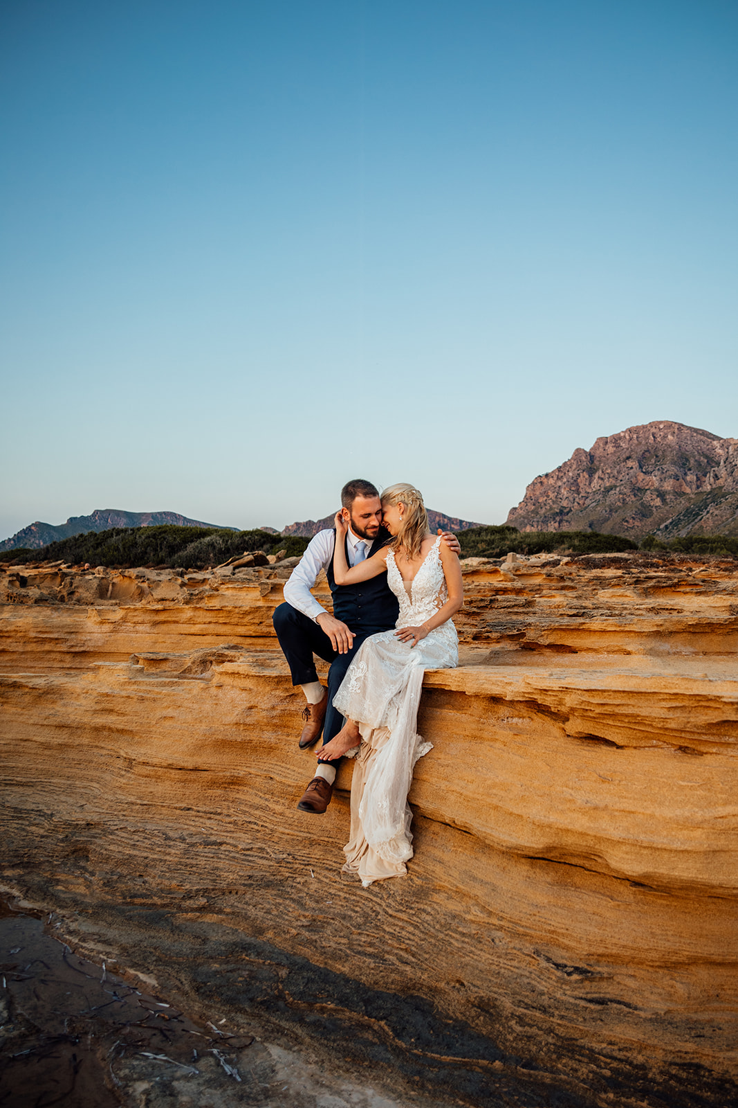 After Wedding Shooting Mallorca - Paar sitzt an Klippen, die orange leuchten 