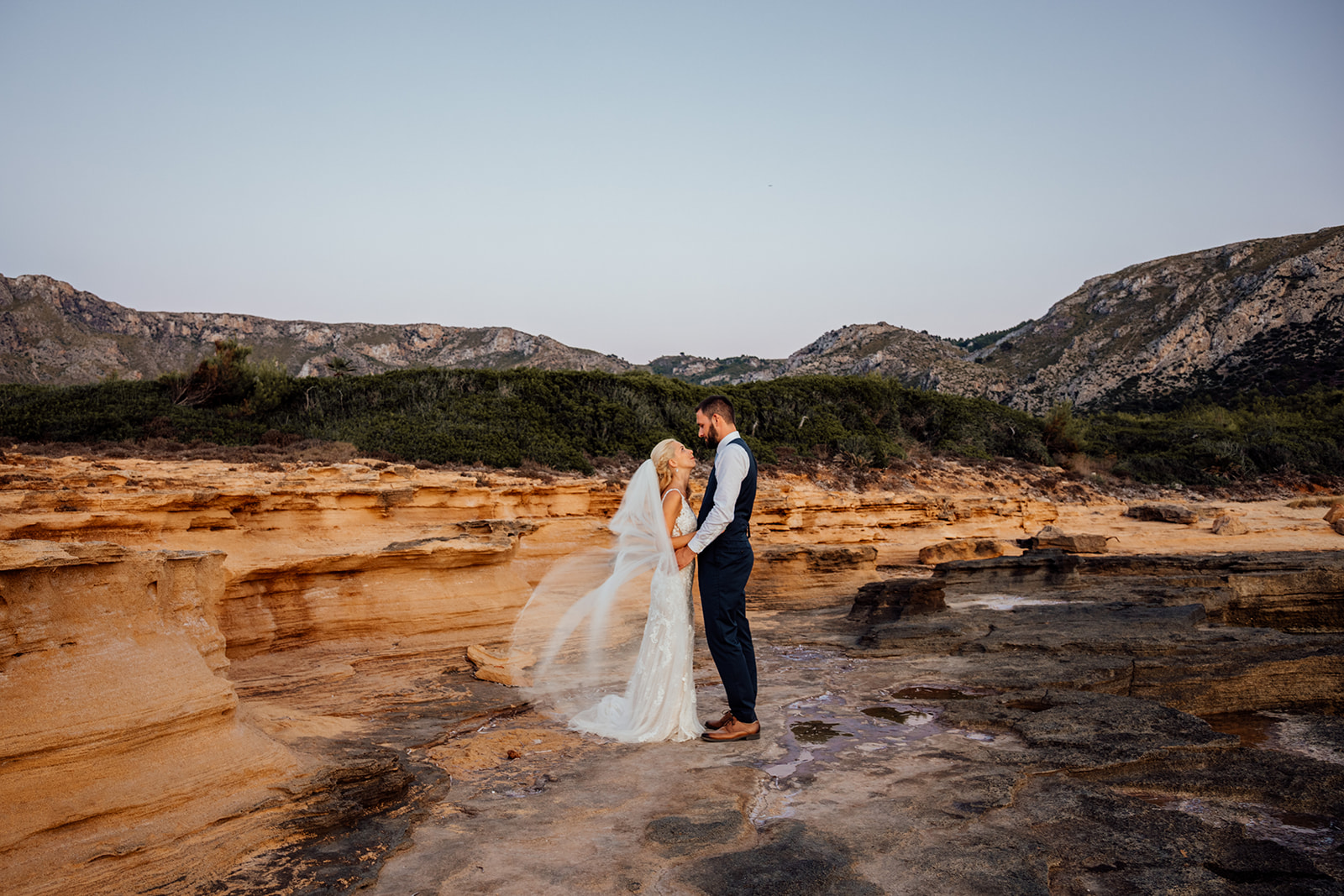 After Wedding Shooting Mallorca - Paar steht am Meer - Schleier weht im Wind 