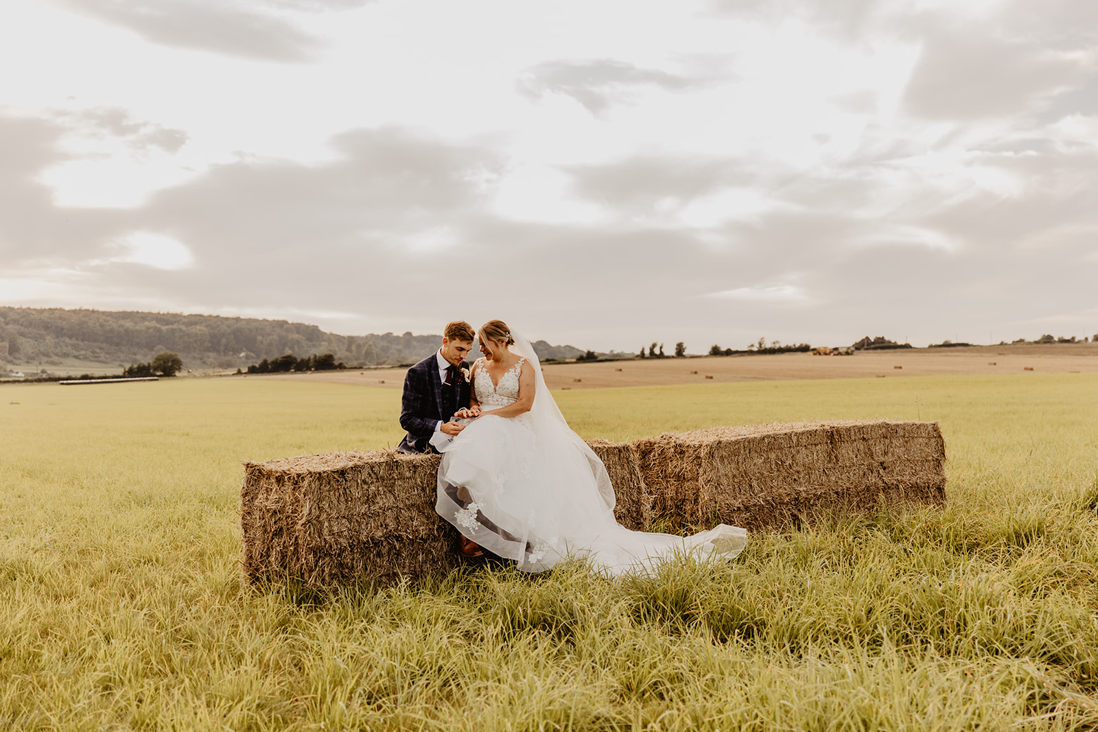 Bride and groom at sunset on hay bail at a wedding at Long Furlong Barn, Sussex. By OliveJoy Photography