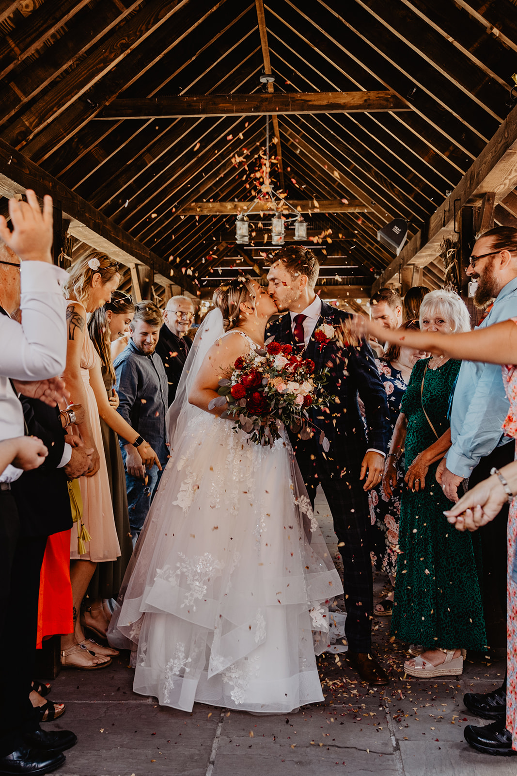 Bride and groom under confetti at a wedding at Long Furlong Barn, Sussex. By OliveJoy Photography.