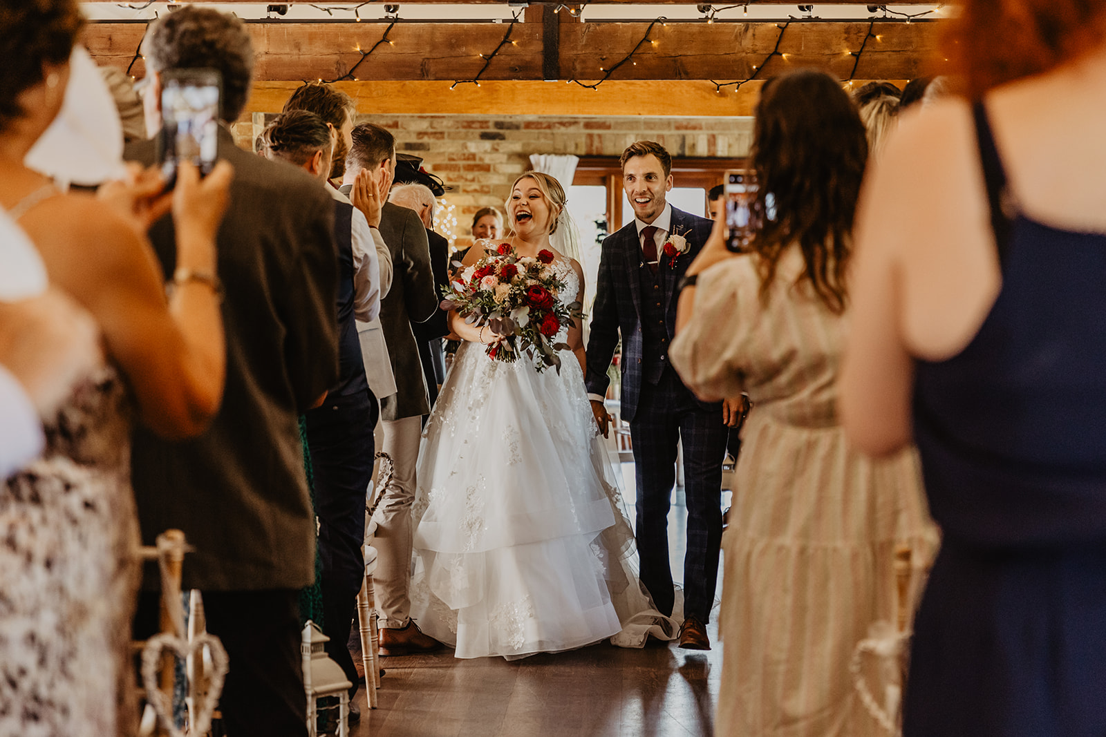Bride and groom walk down the aisle at a wedding at Long Furlong Barn, Sussex. By OliveJoy Photography.