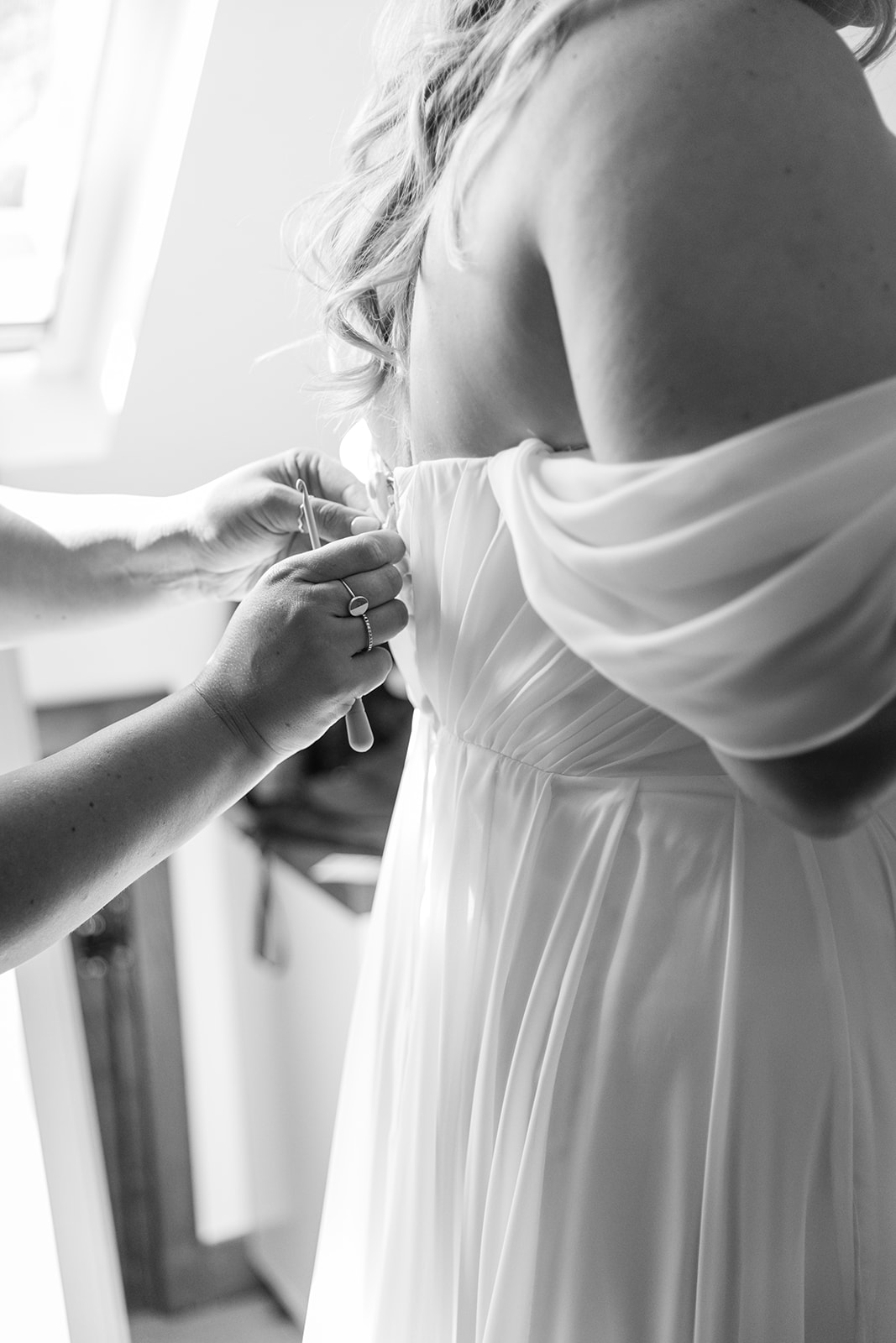 Bride putting on wedding dress at a wedding at Mac's Farm in Sussex. By OliveJoy Photography.