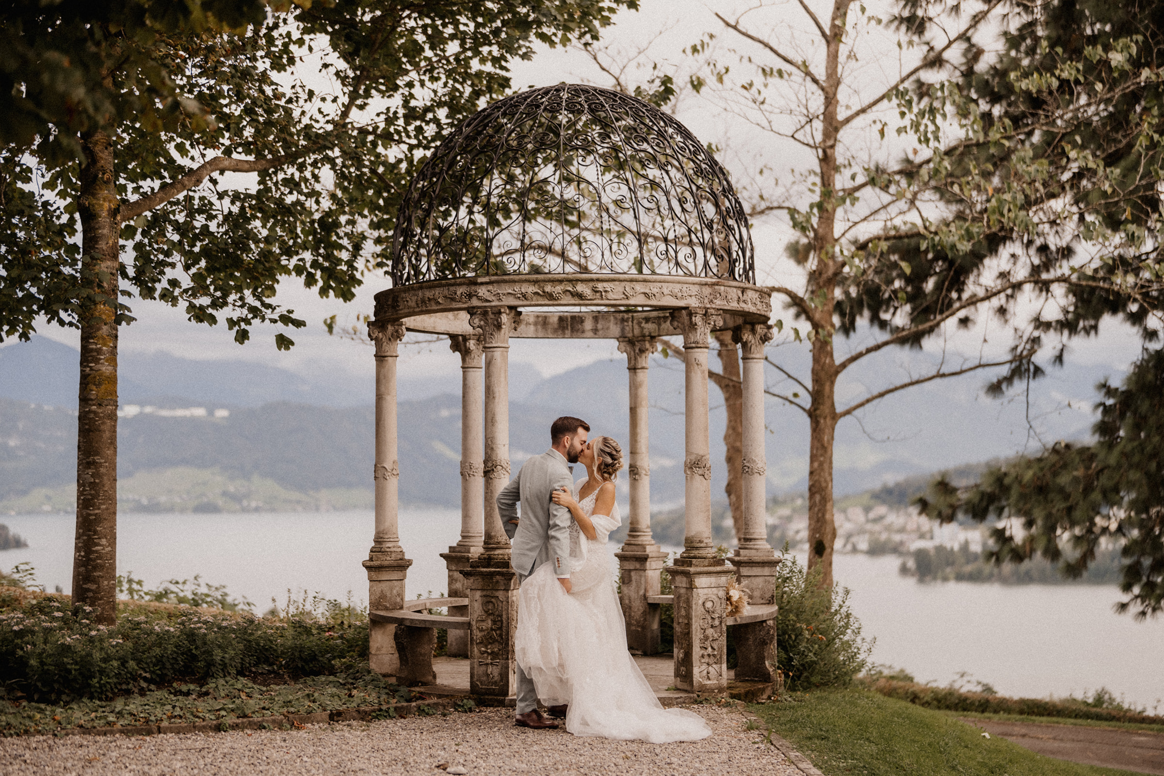 A couple in front of Lake Lucerne on their wedding day leaning in for a kiss