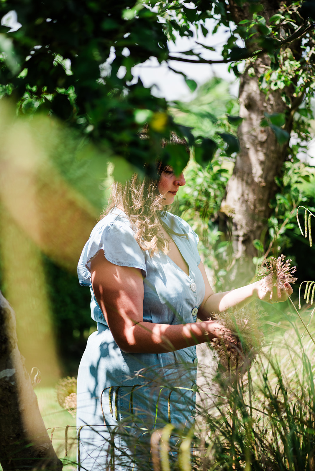 candid personal branding portrait of a designer looking at plants in a garden in Essex