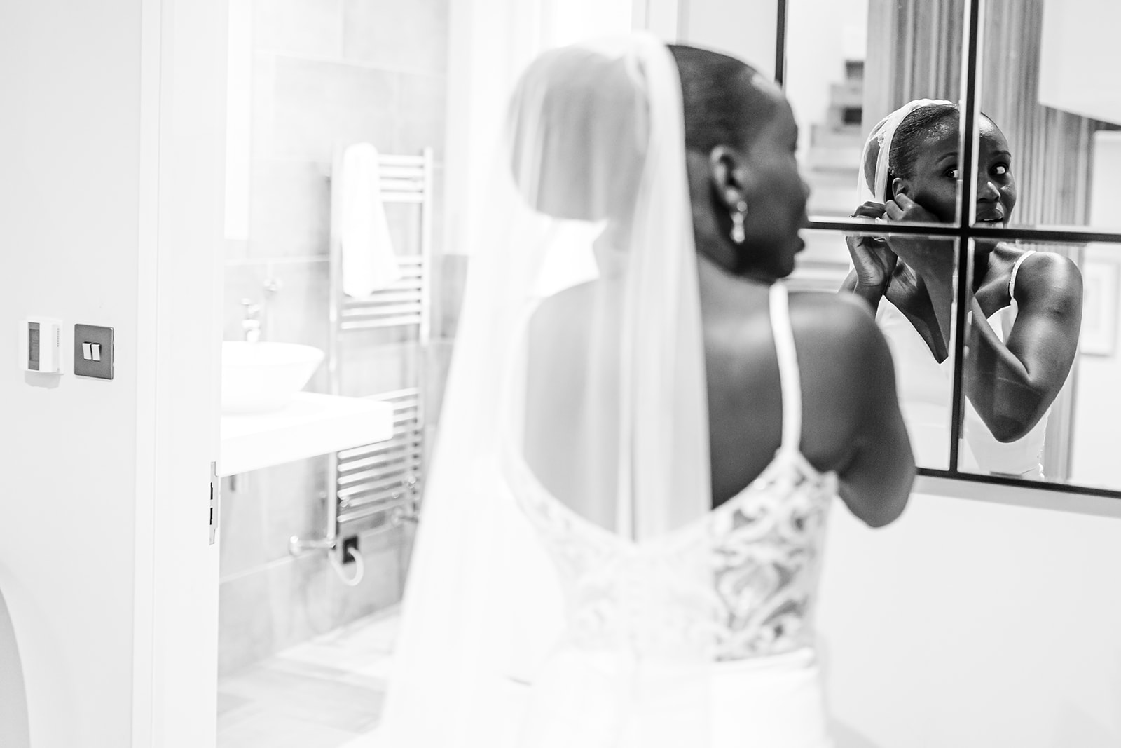 Bride getting ready during bridal prep, putting earings on in front of mirror 