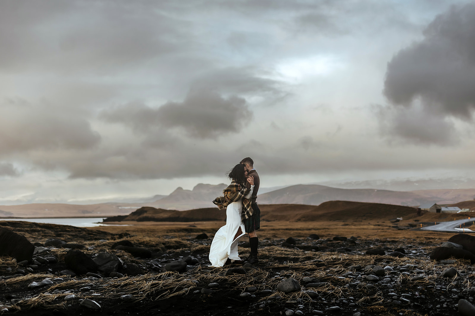 Newlywed couple is hugging on the black sand beach on their Iceland wedding day