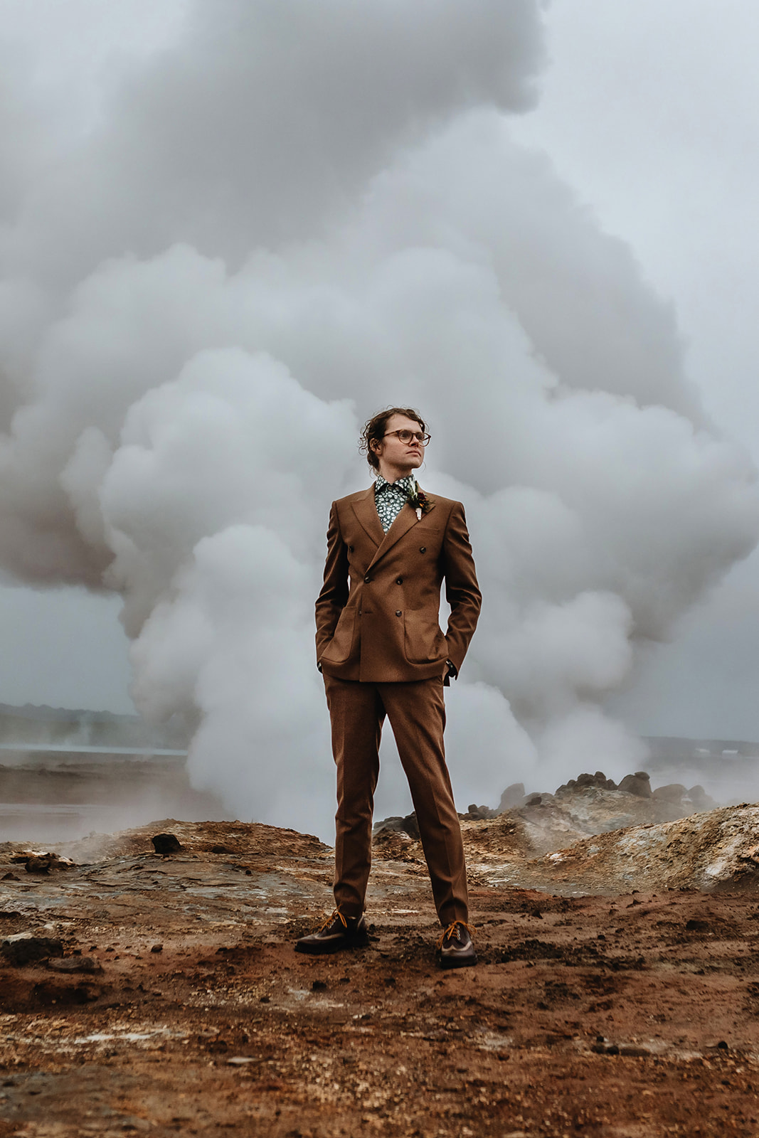 Dramatic shot of a groom in front of a geothermal smoke in Iceland