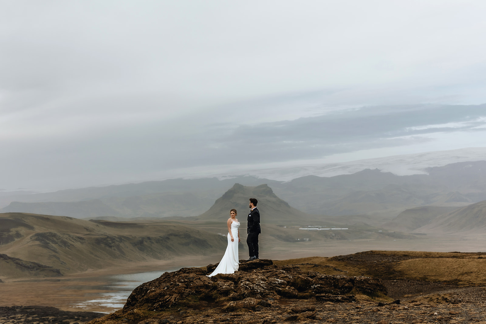 Newlywed couple is standing in a dramatic landscape in Iceland a volcano in the background