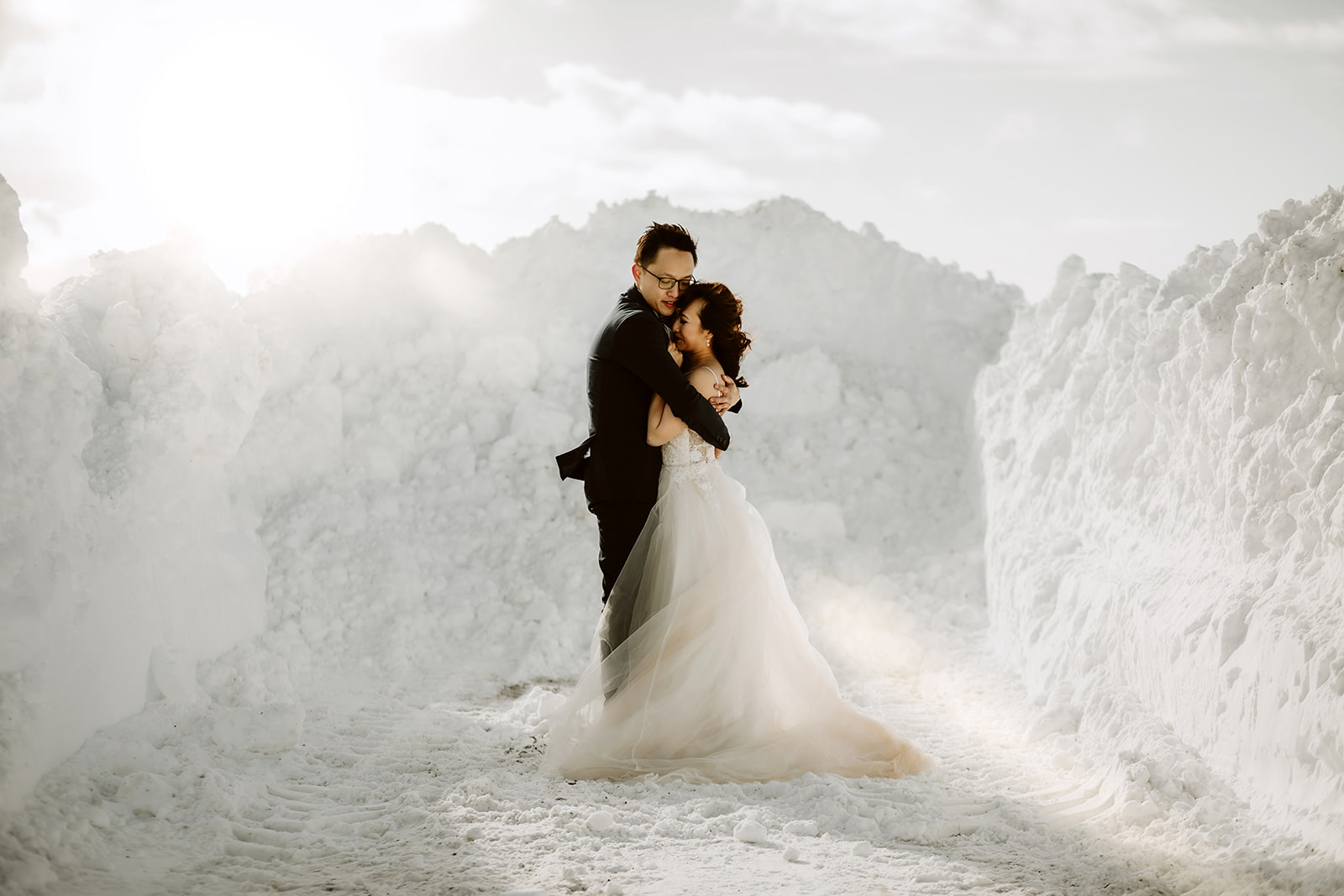 Newlywed couple is hugging in the middle of a snow pile during the winter time in Icelnad
