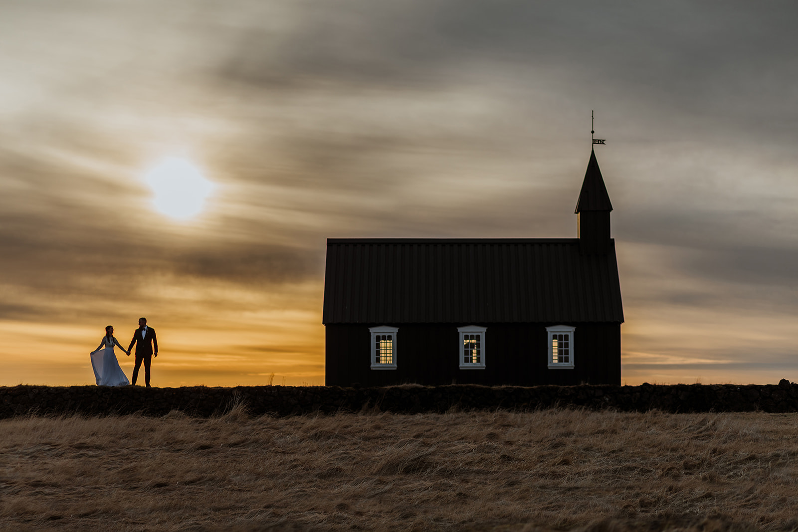 Epic photo os the black church during sunset with a newlywed couple