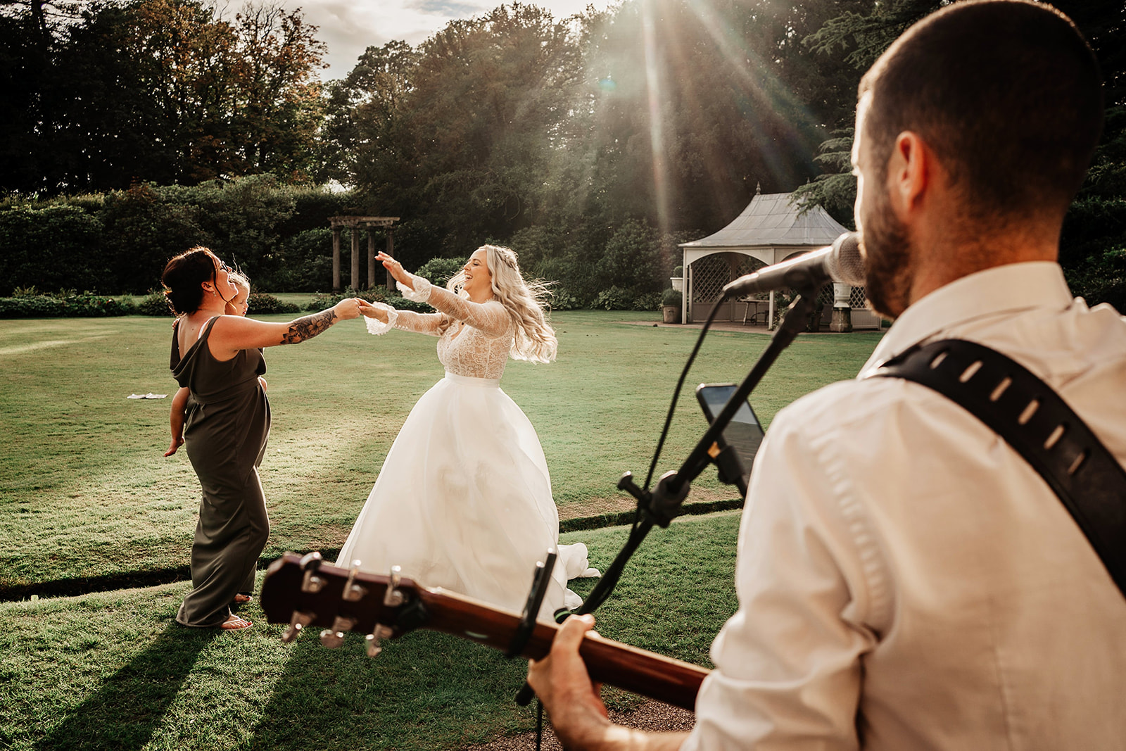 bride dancing with bridesmaid to guitar outside