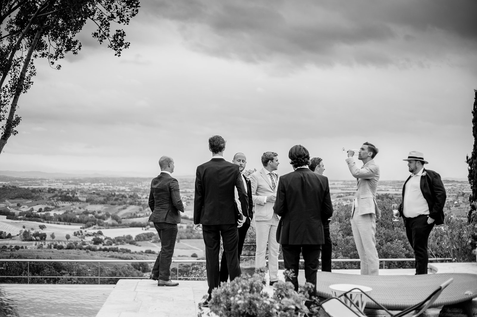 Groom and groomsmen at the terrace of Villa Cicolina drinking beer in front of a beautiful Tuscany landscape