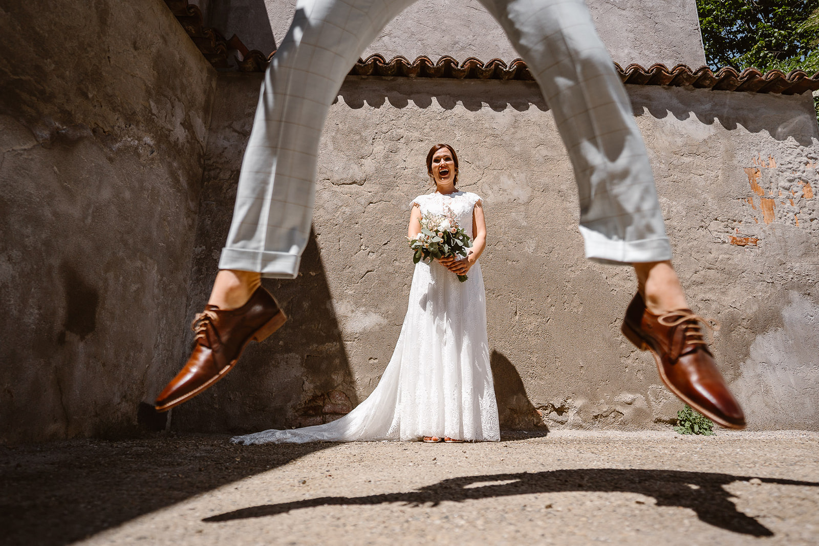 A fun photo of the groom jumping high in front of the bride, with only his shoes visible