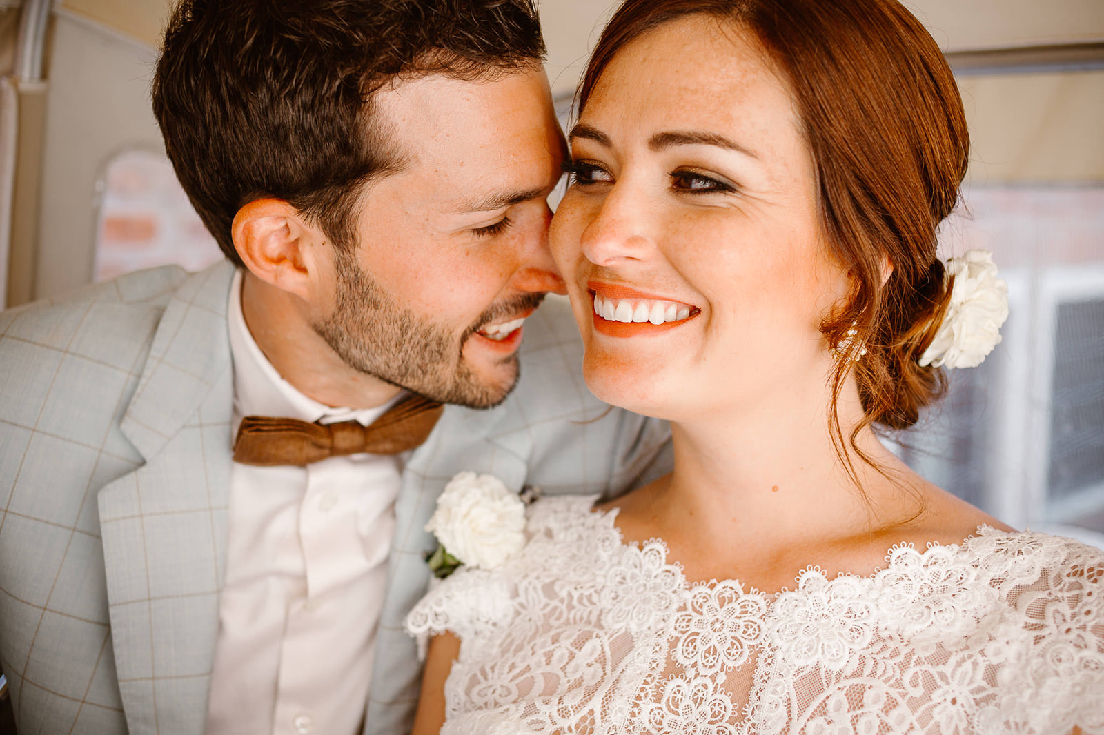 Bride smiling while the groom is cuddling her